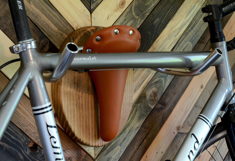 Wall mounted bike rack shaped like a longhorn, made with wood, leather seat, and handlebars – decorative indoor bicycle holder