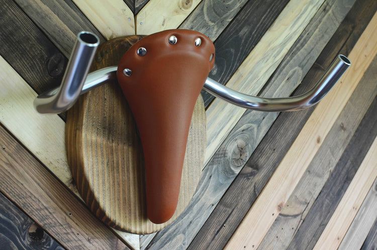 Wall mounted bike rack shaped like a longhorn, made with wood, leather seat, and handlebars – decorative indoor bicycle holder