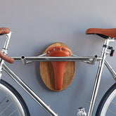 Wall mounted bike rack shaped like a longhorn, made with wood, leather seat, and handlebars – decorative indoor bicycle holder