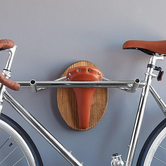 Wall mounted bike rack shaped like a longhorn, made with wood, leather seat, and handlebars – decorative indoor bicycle holder
